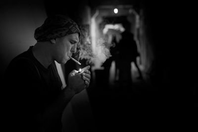 Side view of man smoking cigarette in corridor