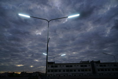 Low angle view of street lights against buildings at dusk