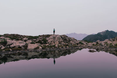 Man standing on rock against sky