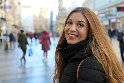 Portrait of smiling woman standing in city during winter