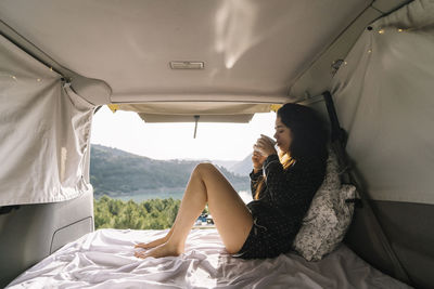 Woman drinking coffee in van at vacation