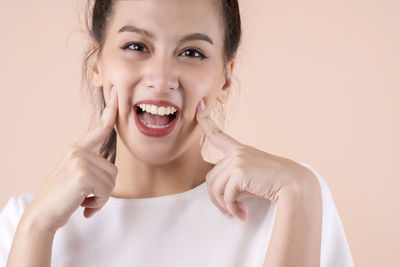 Portrait of smiling young woman against wall