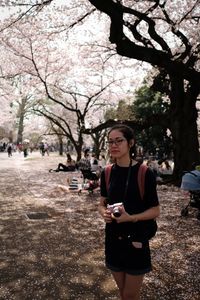 Full length of woman standing by tree in city