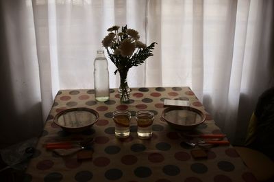 Flower vase and glasses on table at home