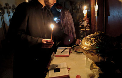 Midsection of man holding illuminated lighting equipment on table