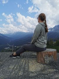 Full length of man sitting on wood against sky