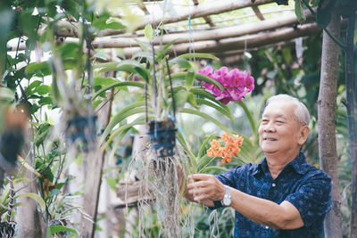 Young man with pink flowers in garden