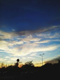 Low angle view of silhouette trees against cloudy sky