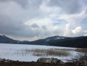 Scenic view of lake by snowcapped mountains against sky