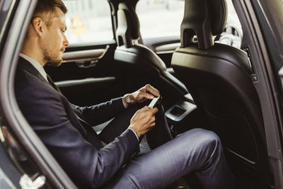 Side view of businessman using smart phone while sitting in car