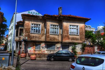 Cars on street by buildings against blue sky