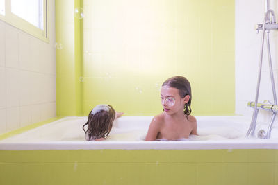 Siblings playing in bathtub