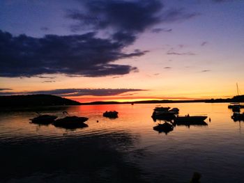 Silhouette boats in sea against sky during sunset