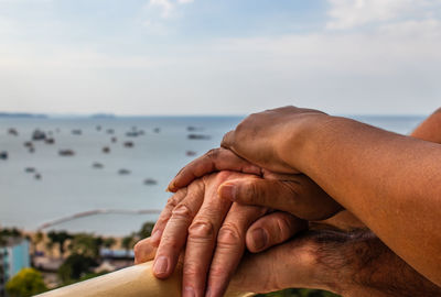 Midsection of man holding hands against sea against sky