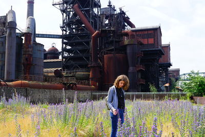 Woman standing on field against factory