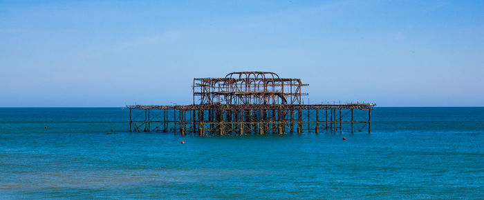 Crane by sea against clear blue sky