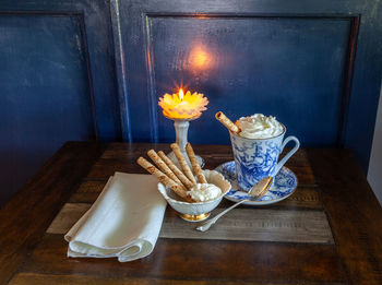 Gourmet hot chocolate and whip cream in a nautical china mug with cookies on a rustic table 