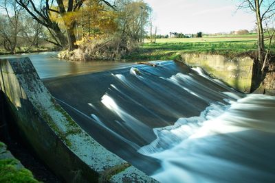 Scenic view of water by trees against sky