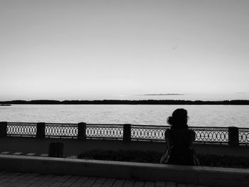 Rear view of silhouette woman standing by sea against clear sky