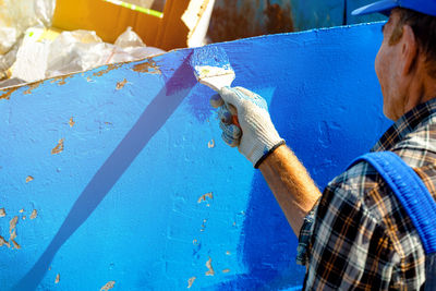 Rear view of man painting on wall