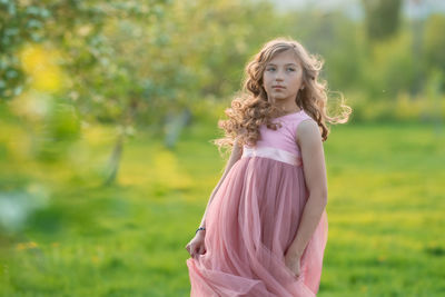 Portrait of woman with pink flower standing on field