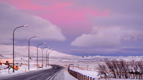 Snow covered landscape against sky during sunset