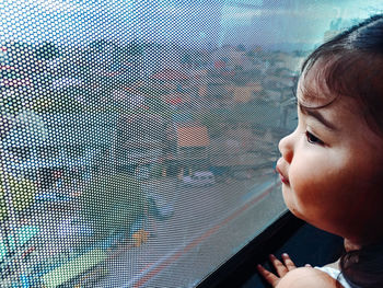 Close-up portrait of boy looking through window