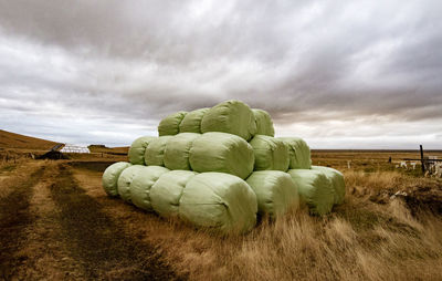 Hay bales on field against sky