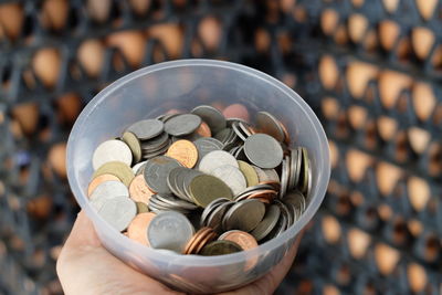 Cropped hand holding coins in container