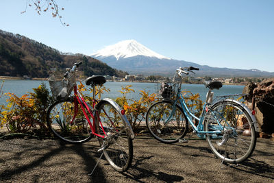 Bicycles on street by lake against sky
