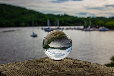 Close-up of crystal ball with reflection on water at a marina.