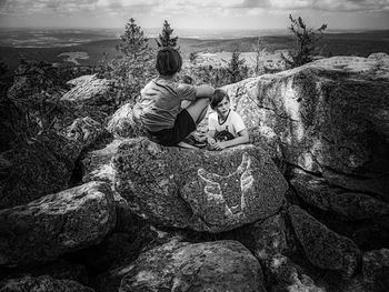 Rear view of two boys sitting on rock