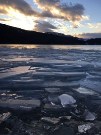 Surface level of frozen lake against sky during sunset