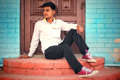 Full length of young man sitting on front hoop against closed door