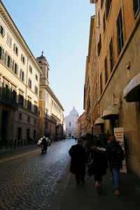Rear view of people walking on street in city
