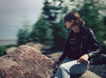 Woman sitting on rock looking away
