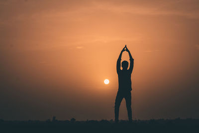 Silhouette person standing on field against sky during sunset