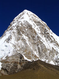 Low angle view of snowcapped mountain against clear blue sky