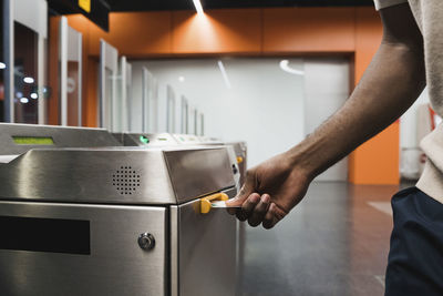 Hand of man inserting metro ticket in electronic barrier
