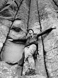 Low angle view of young woman with arms outstretched standing at giants causeway