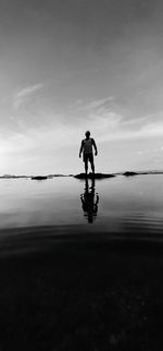 Rear view of silhouette man riding bicycle in water