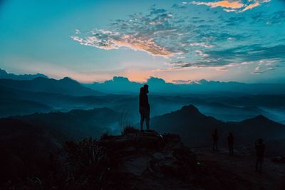 Silhouette man standing on mountain against sky during sunset