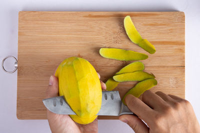 Midsection of person holding fruits on cutting board