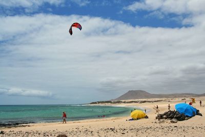 People paragliding at beach against sky