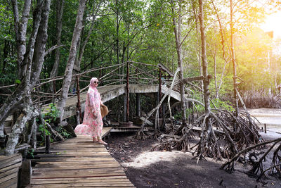Woman standing by tree trunk in forest