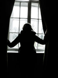 Young woman looking through window