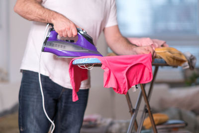 Midsection of man ironing top on board