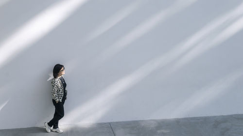 Woman standing on the sunny wall