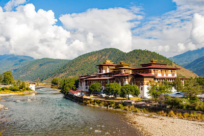 River by temples and mountains against cloudy sky