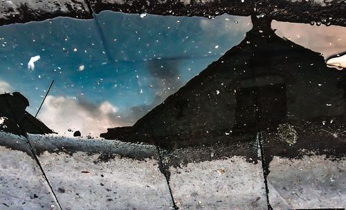 Silhouette person by window against sky during winter